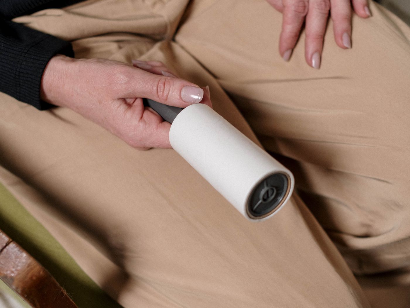 A person using a lint roller to remove pet hair from clothing at home.